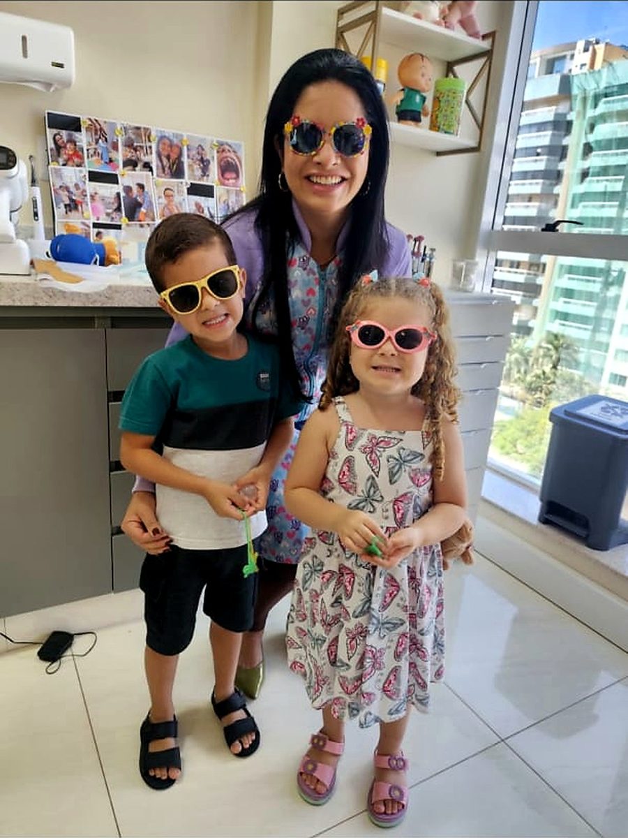 Dra. Camila Melo com dois pacientes no consultório