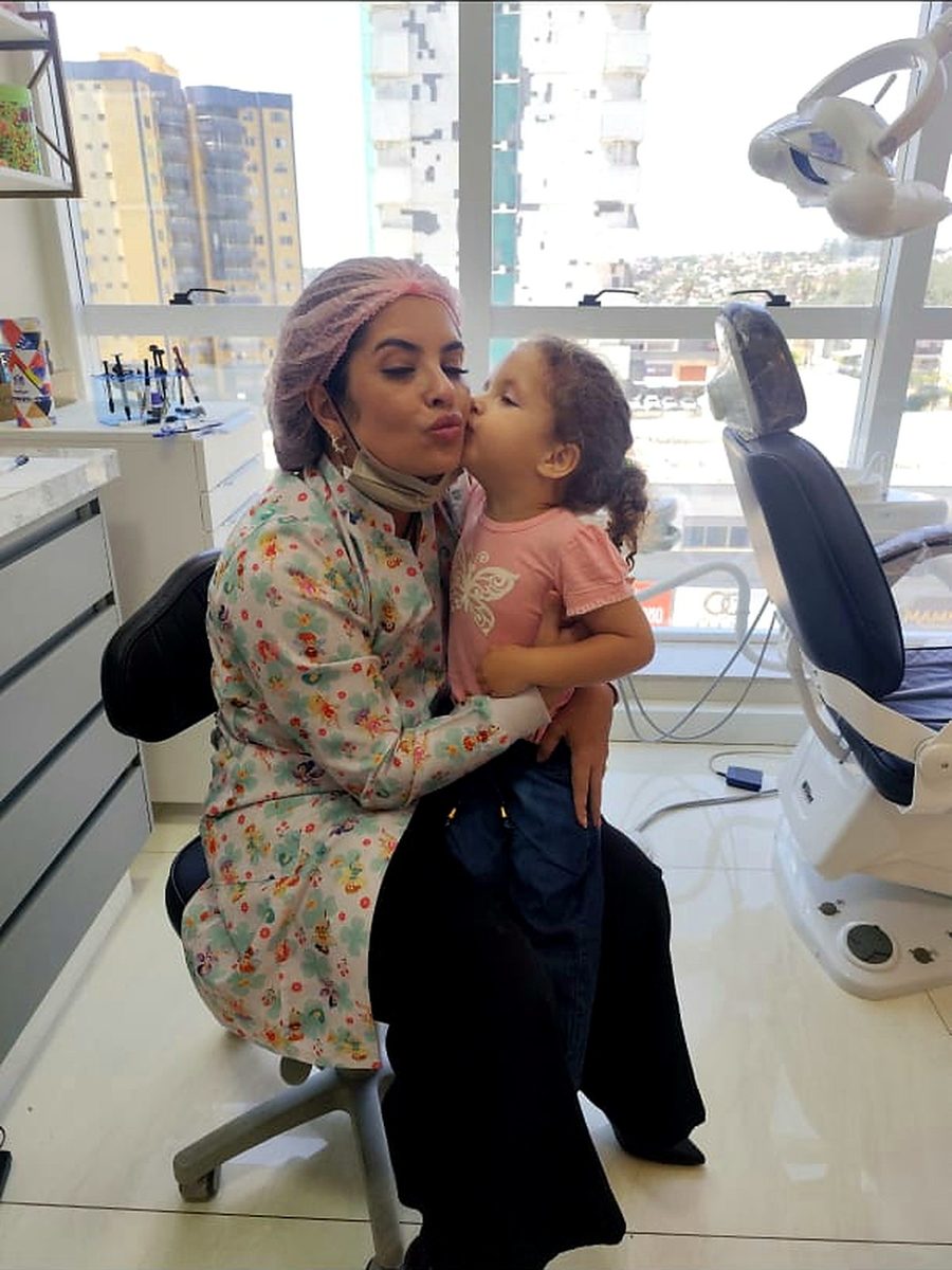 Dra. Camila Melo acolhendo criança no colo durante a consulta