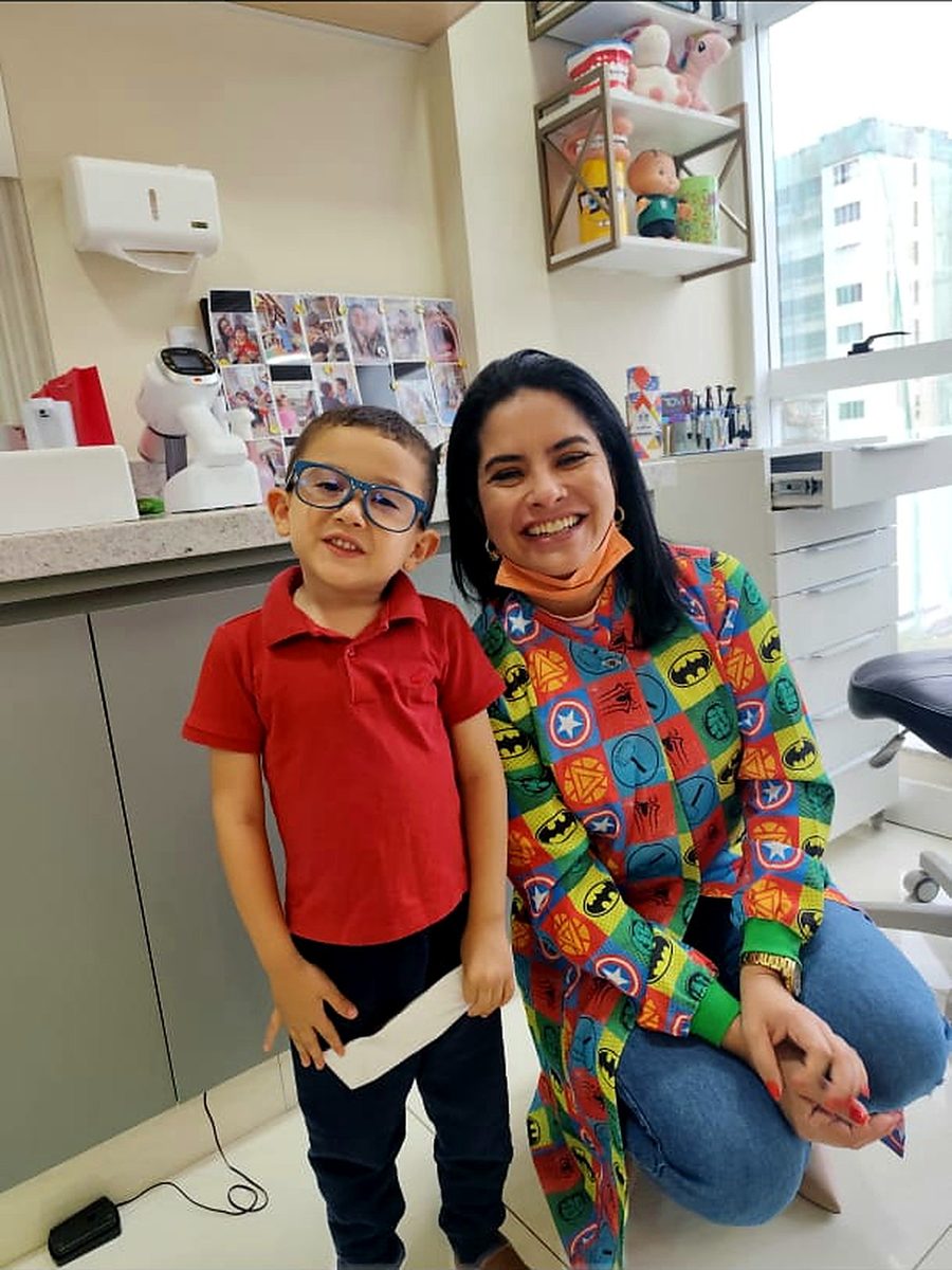 Paciente sorrindo ao lado da Dra. Camila Melo no consultório